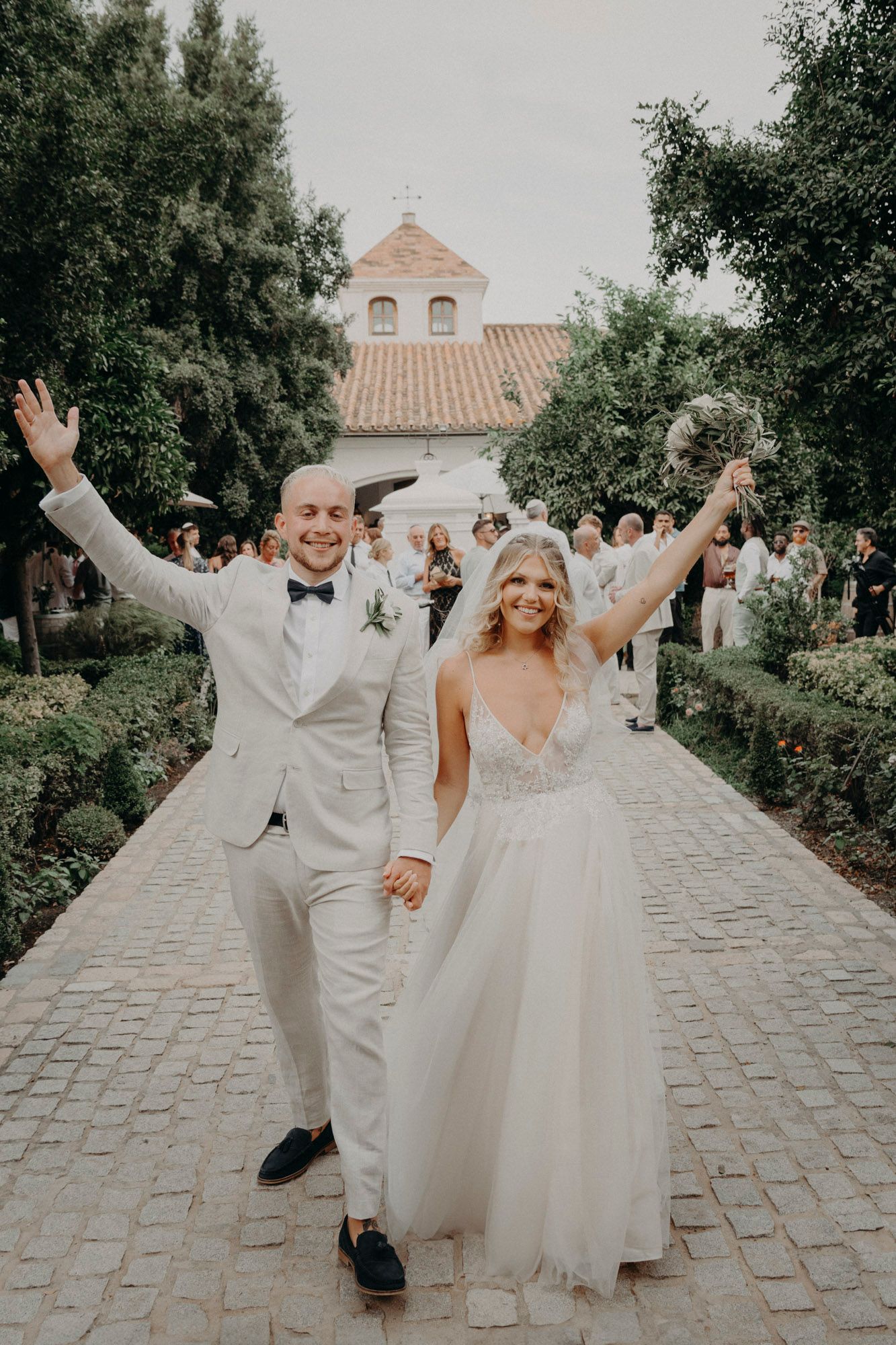 Newlyweds celebrating with joyful raised arms while exiting their wedding ceremony at a charming chapel.