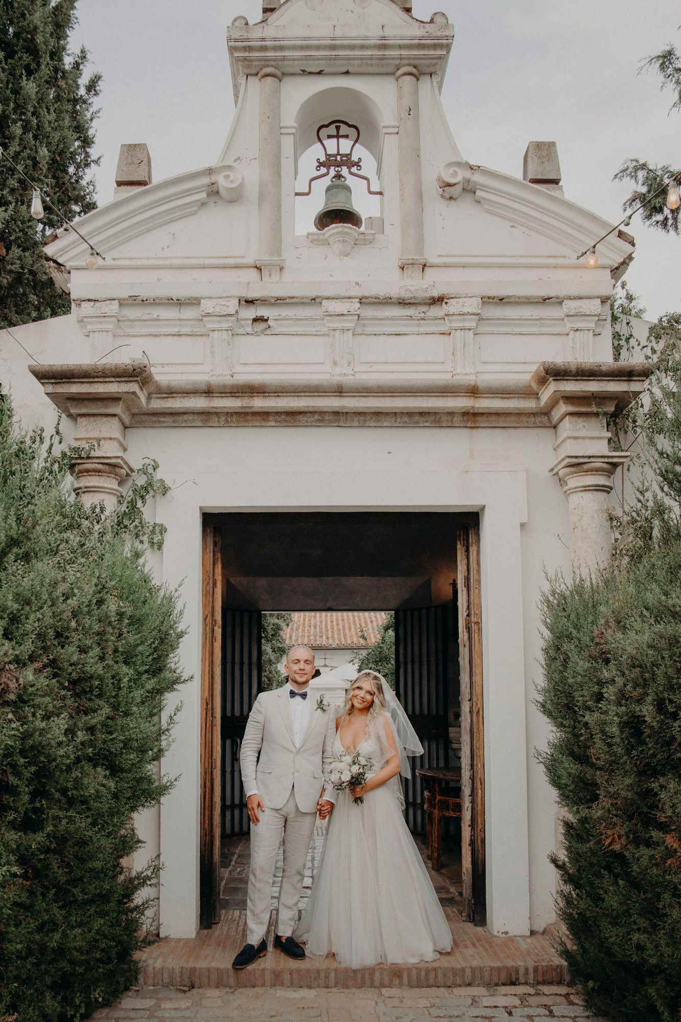 A classic white Spanish-style church entrance frames the happy newlyweds on their special day.