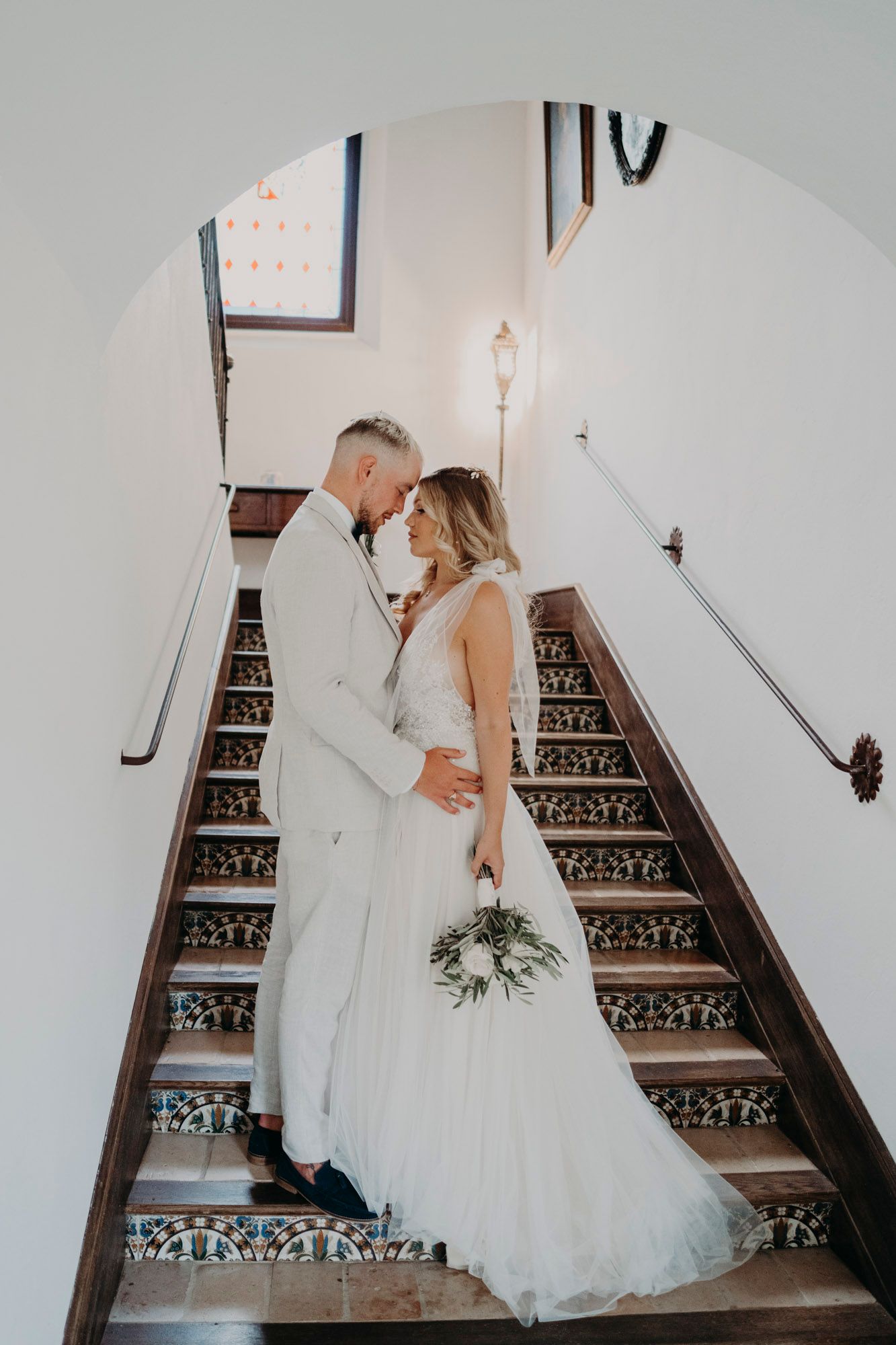 Romantic wedding couple shares intimate moment on vintage staircase with ornate details.