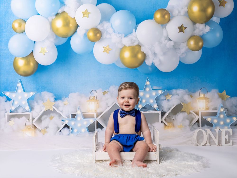 Baby during cloud-themed cake smash in Glenview IL studio with gold stars, white balloons, and dreamy backdrop for first birthday.