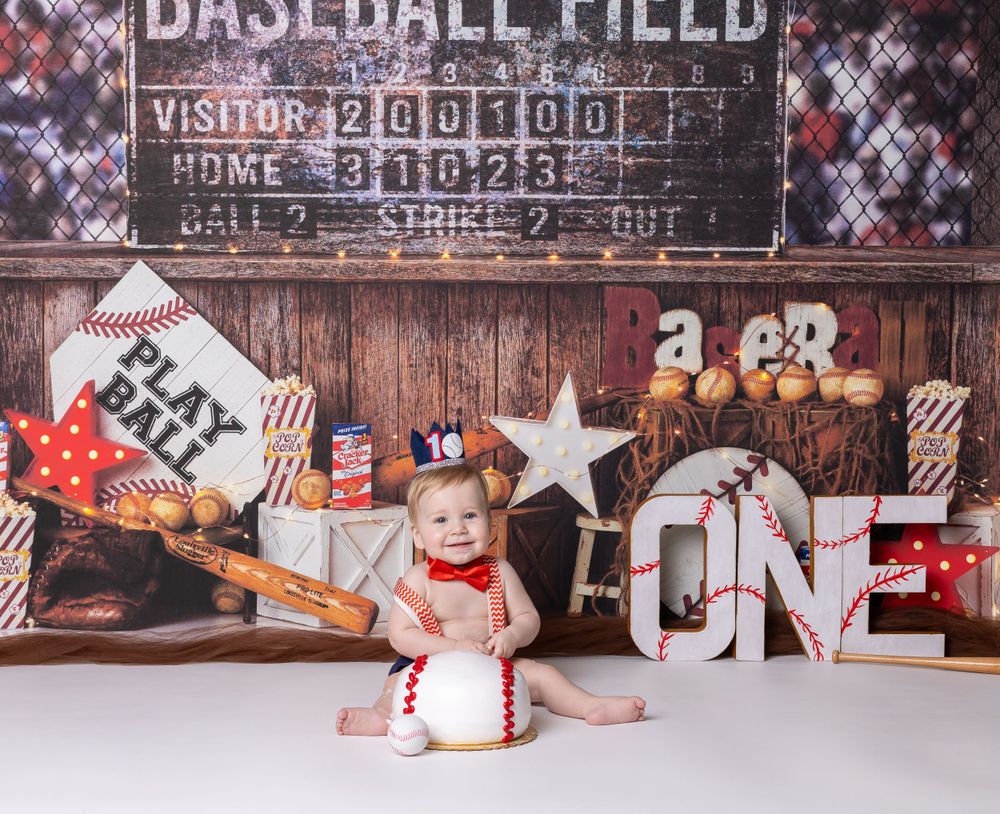 Baby celebrating first birthday with baseball-themed cake smash in Glenview IL studio featuring bats, scoreboard, and fun props.