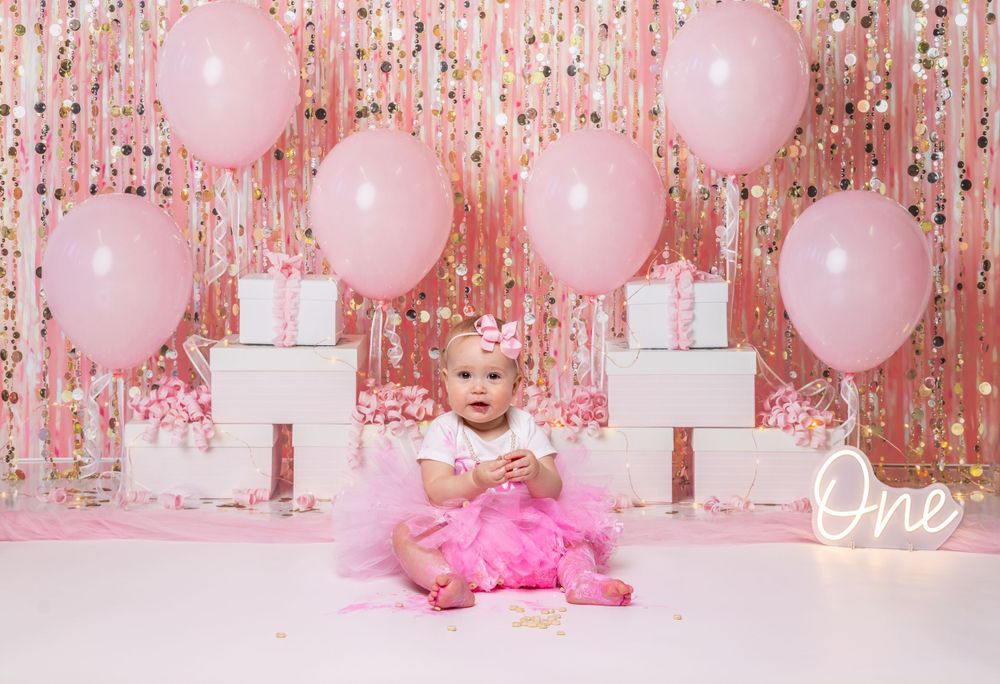 Baby during Glam Gem-themed cake smash in Glenview IL studio featuring pink balloons, glitter backdrop, and elegant decor for first birthday