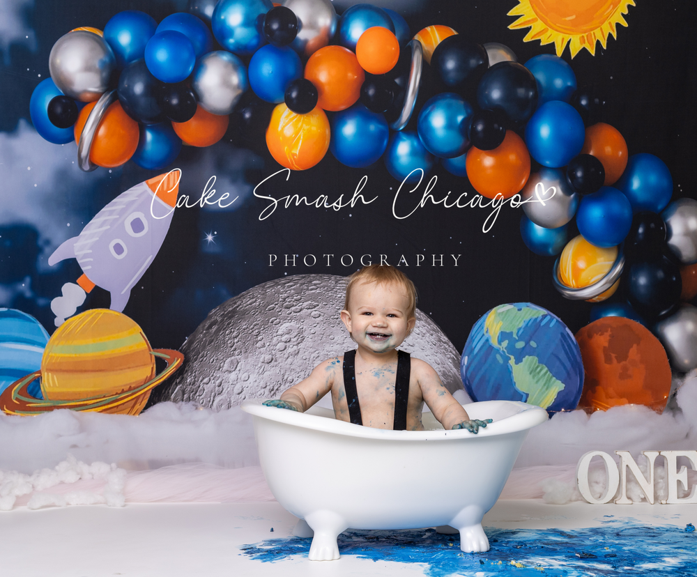 Baby during astronaut-themed cake smash in Glenview IL studio featuring planets, rockets, and space-inspired decor for first birthday bath.
