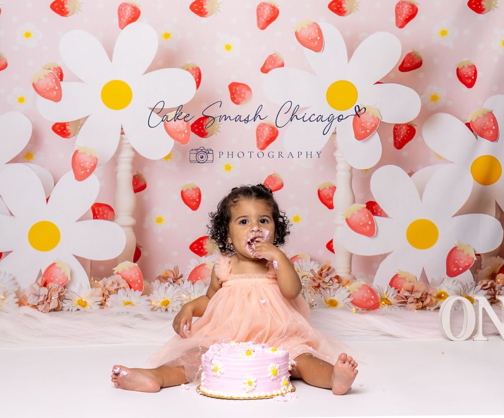 Baby during berries and daisies-themed cake smash in Glenview IL studio featuring daisy backdrop, strawberries, and whimsical decor.
