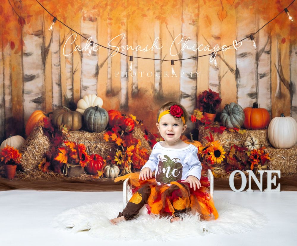 Baby during fall-themed cake smash in Glenview IL studio featuring pumpkins, autumn leaves, and rustic decor for first birthday.