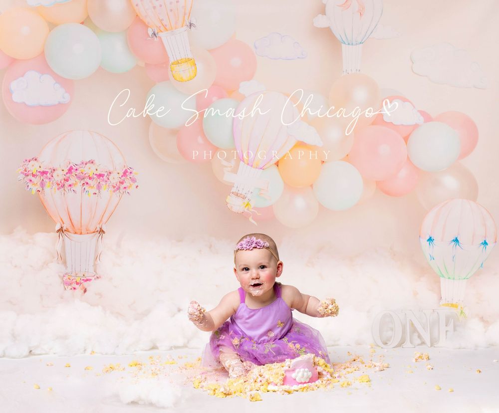 Baby during hot air balloon-themed cake smash in Glenview IL studio with pastel balloons, dreamy decor, and matching cake for first birthday