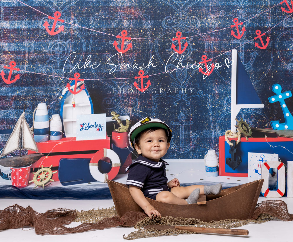 Baby during sailor-themed cake smash in Glenview IL studio featuring nautical decor, anchors, boats, and ocean-inspired setup for first birt