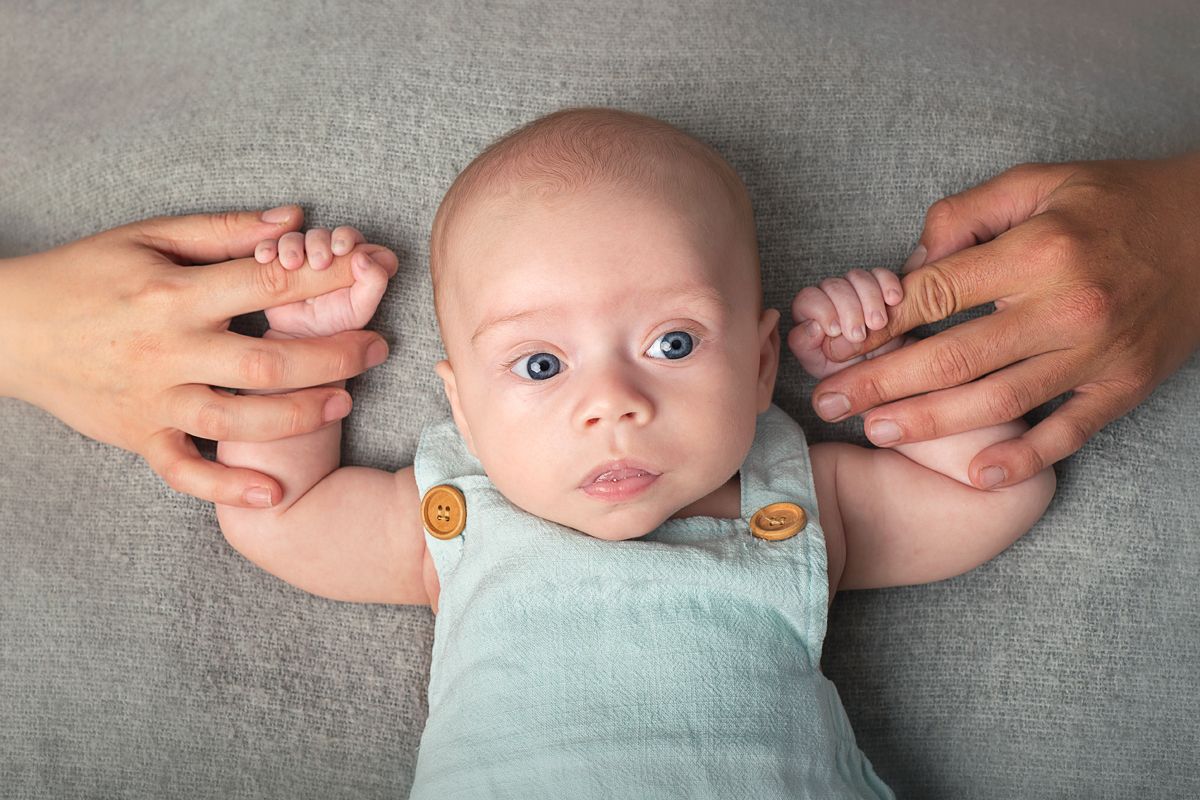 close up of little four month baby boy holding parents fingers for milestone session in Northumberland Ontario *