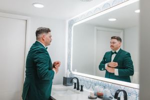 Wedding preparation scene in modern bathroom with illuminated mirror.