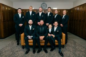 Wedding party getting ready in modern room with black suits.