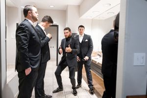 Creative wedding photo of couple holding hands around corner in modern hallway.
