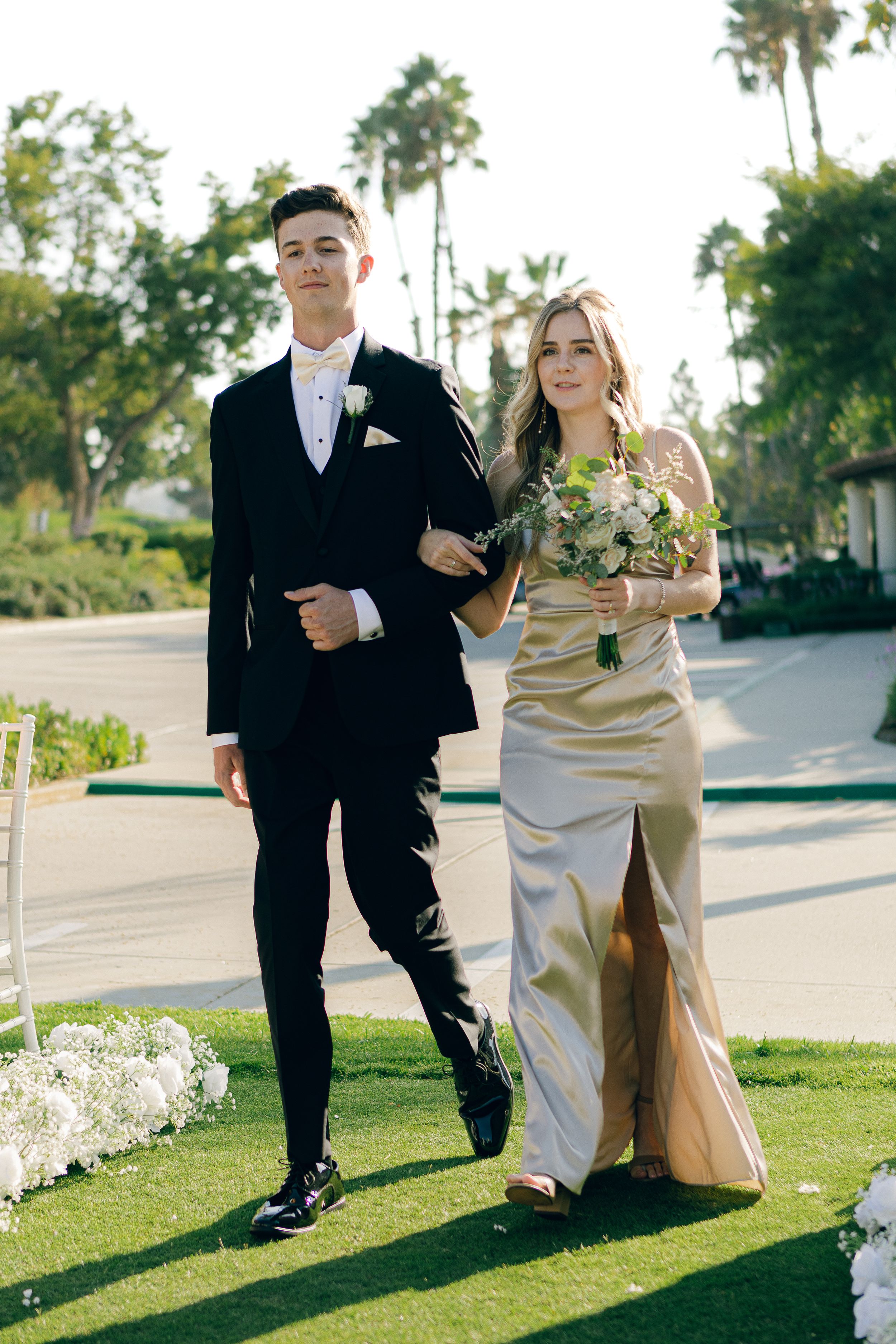 A romantic outdoor wedding kiss with white floral arch and pond in background.
