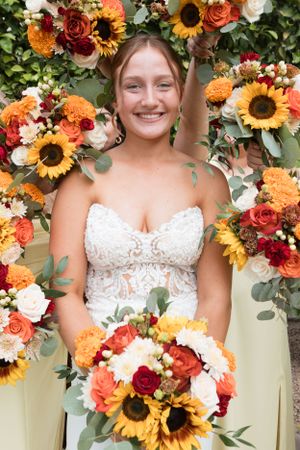 Beautiful bridal portrait surrounded by vibrant sunflowers and fall-colored floral arrangements.