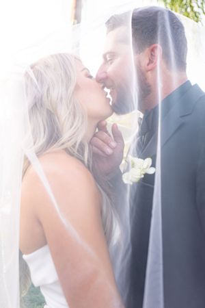 Dreamy wedding portrait through sheer veil with soft, ethereal lighting.