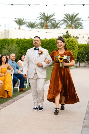 Wedding party members walking down aisle in autumn-themed attire.