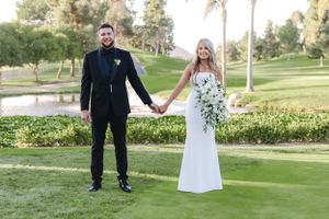Elegant wedding portrait of couple standing on golf course with water feature and palm trees.