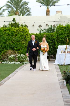 Wedding processional on concrete path with desert landscaping.