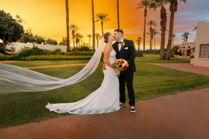 Sunset wedding portrait with flowing veil and palm trees in background.