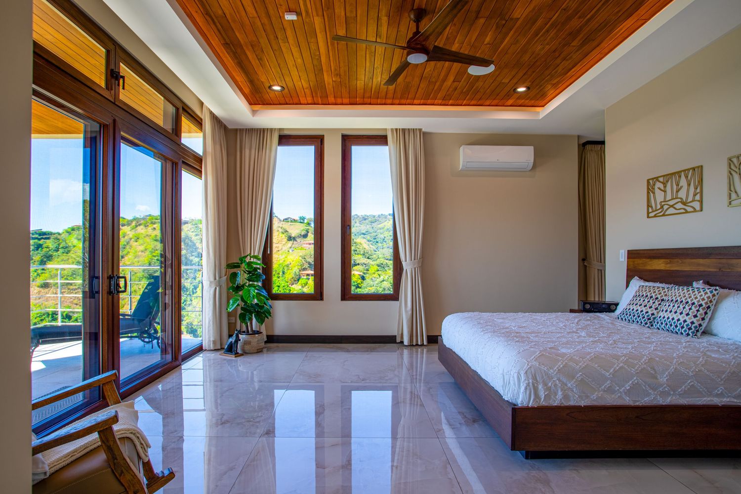 Elegant master bedroom with wooden ceiling, large windows, and contemporary decor in a luxury home