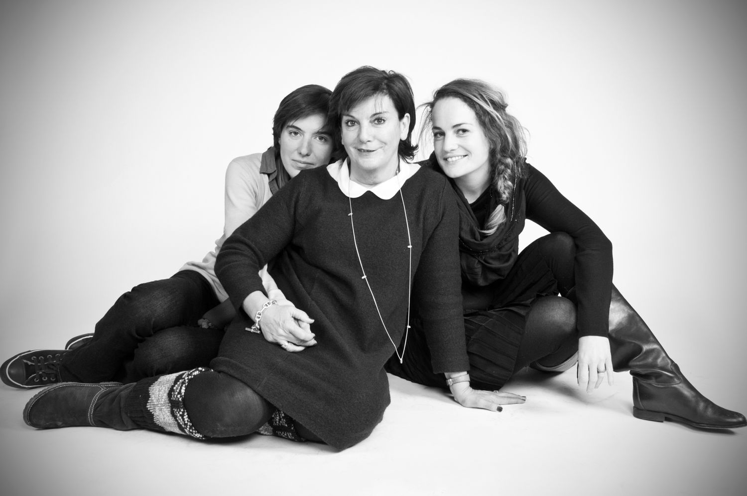 Black and white studio portrait of people laying on the floor in casual wear.