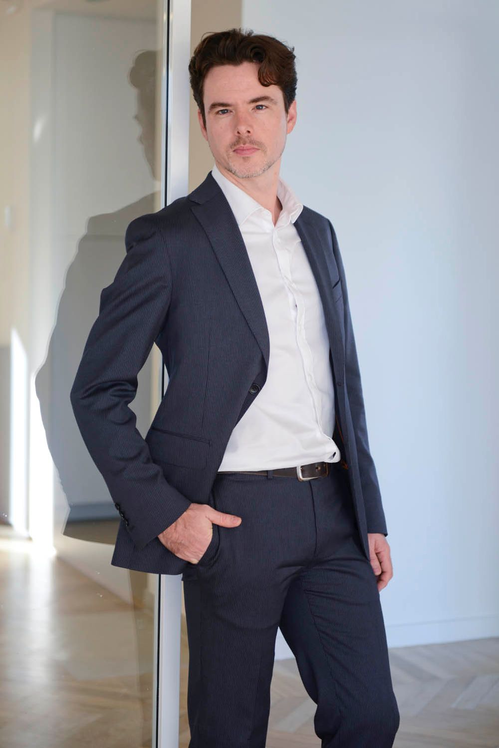 Professional portrait series showing someone in a dark suit against a white background.
