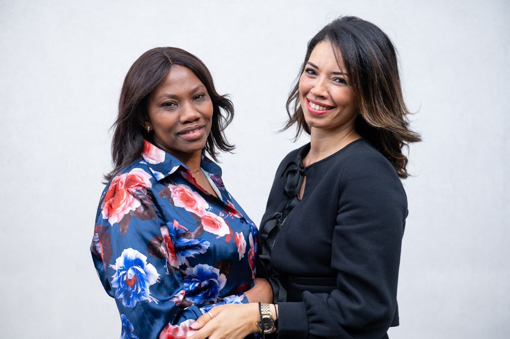 Two colleagues sharing a joyful moment in professional attire.