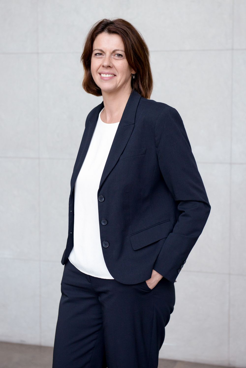 Professional portrait of person wearing navy business suit and white top.