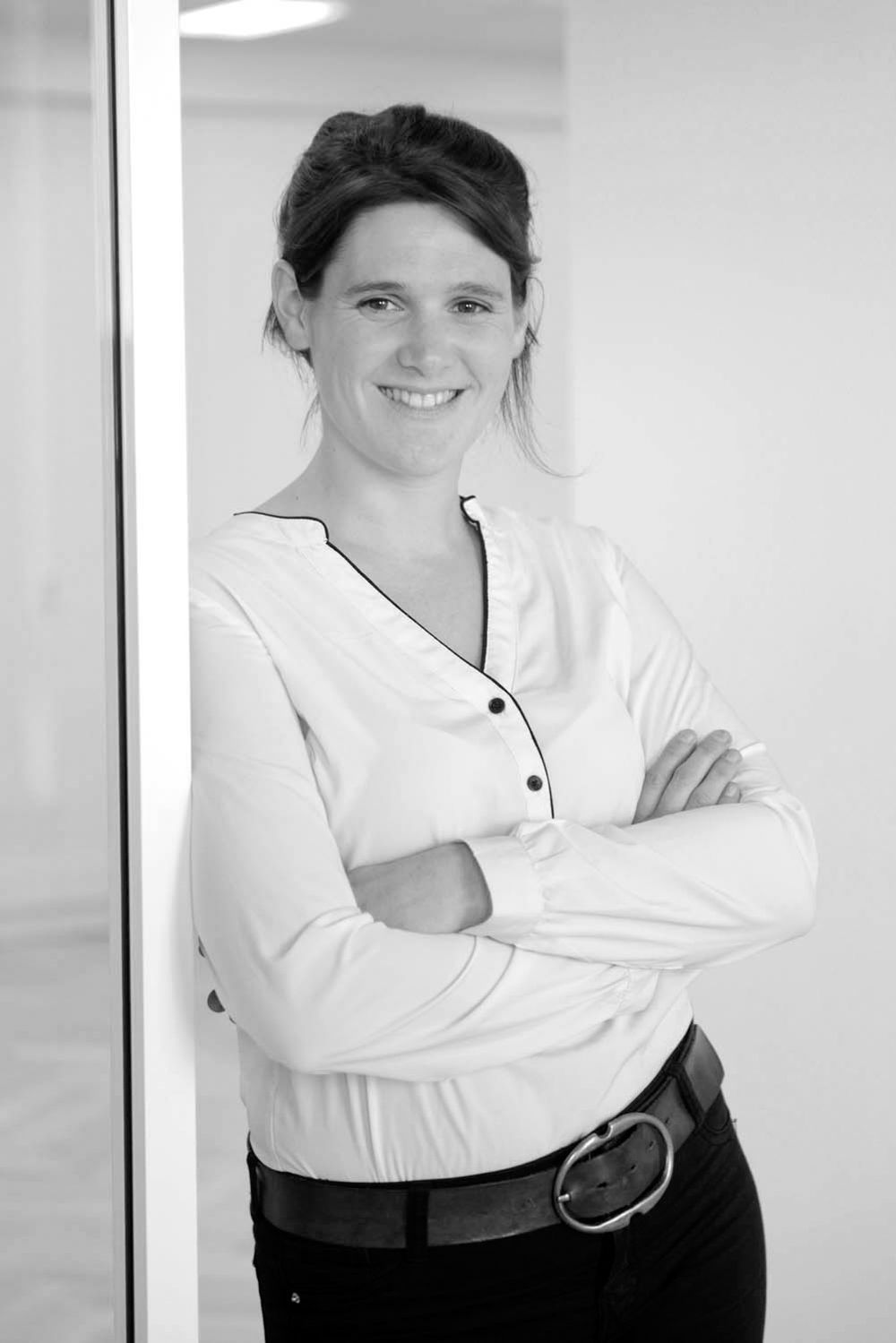 Professional staff member in white uniform and black apron poses with crossed arms.