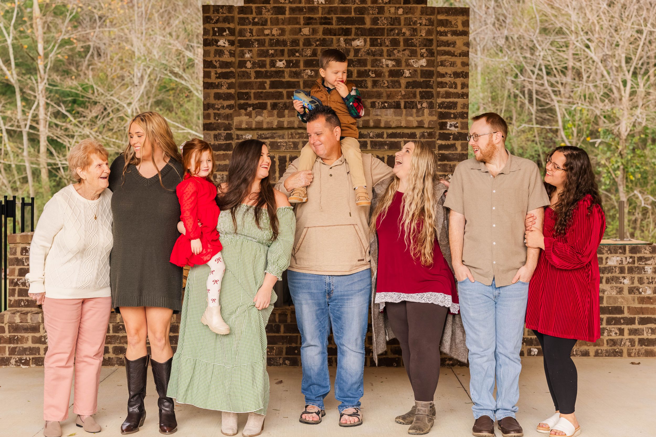 Group of people wearing casual clothing pose against brick wall.