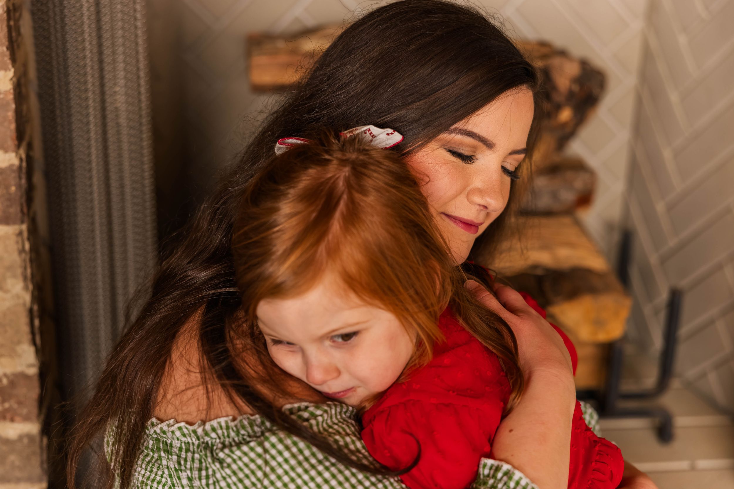 Tender moment between family members embracing against brick wall.