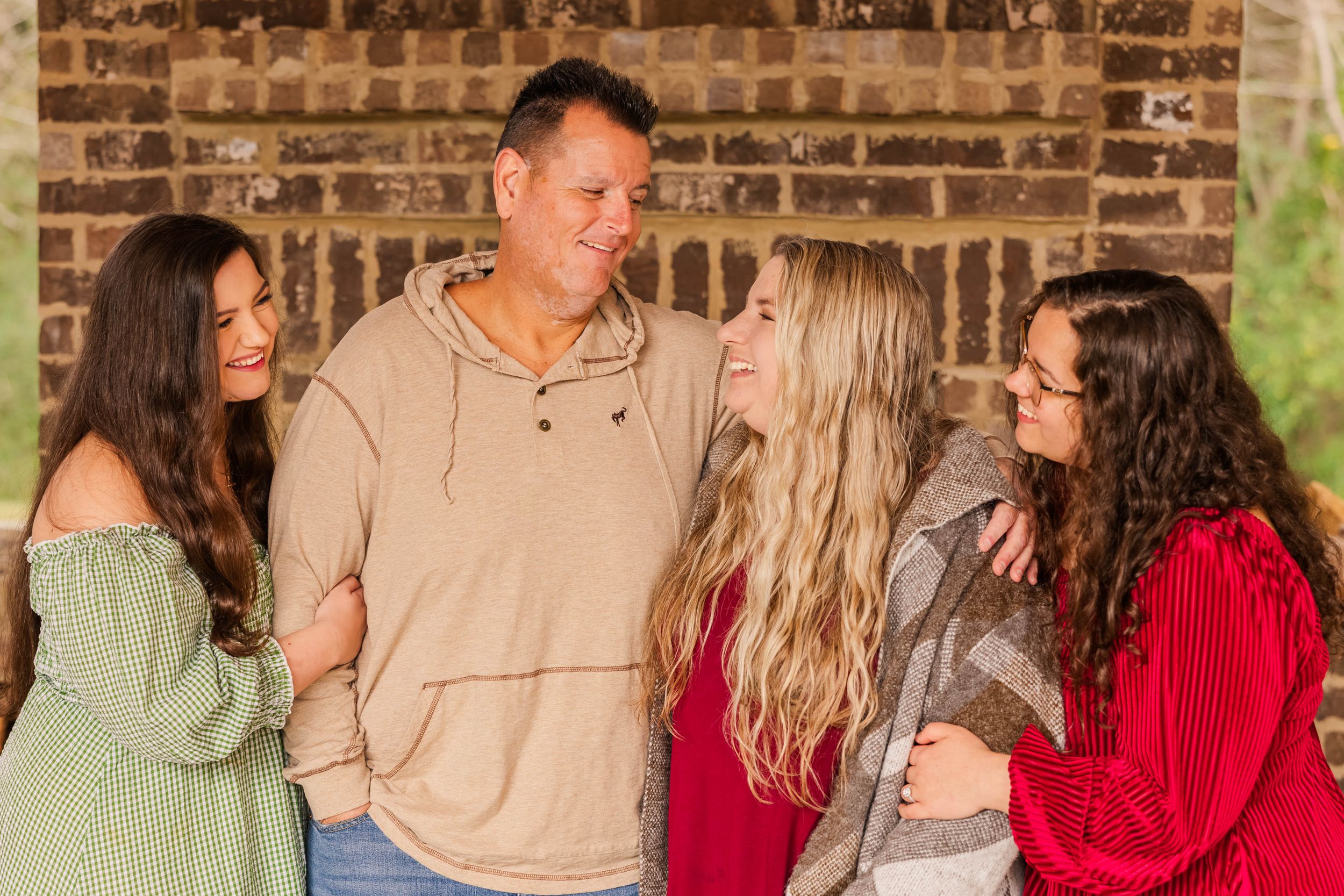 Group of four people share candid moment together against brick wall.