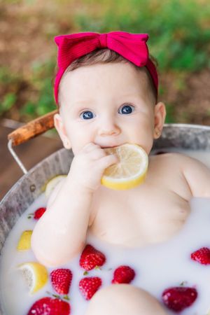 Milk bath portrait with floating citrus slices and fresh raspberries.