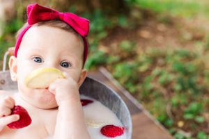 Playful milk bath scene with citrus slices and bright red raspberries.