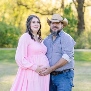 Couple in pink dress and cowboy hat share romantic moment in golden sunlit field.