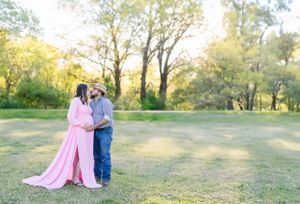 Happy couple posing together in pastoral field setting during golden hour.