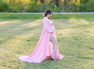 Side profile of pregnant woman in flowing pink dress against natural outdoor backdrop.