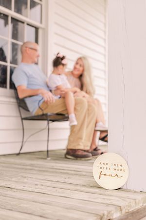 A tender moment shared on a white porch bench during a sunny day, showing closeness and affection.