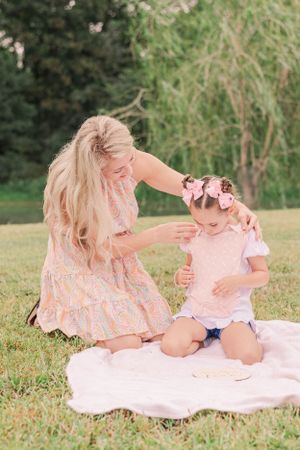 Family having playful moment together on white blanket in sunny outdoor setting.