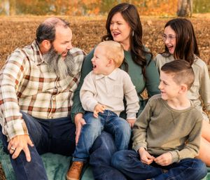 Family laughing together while sitting on blanket during fall photo session.