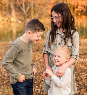 Three people sharing a joyful moment outdoors in fall scenery.