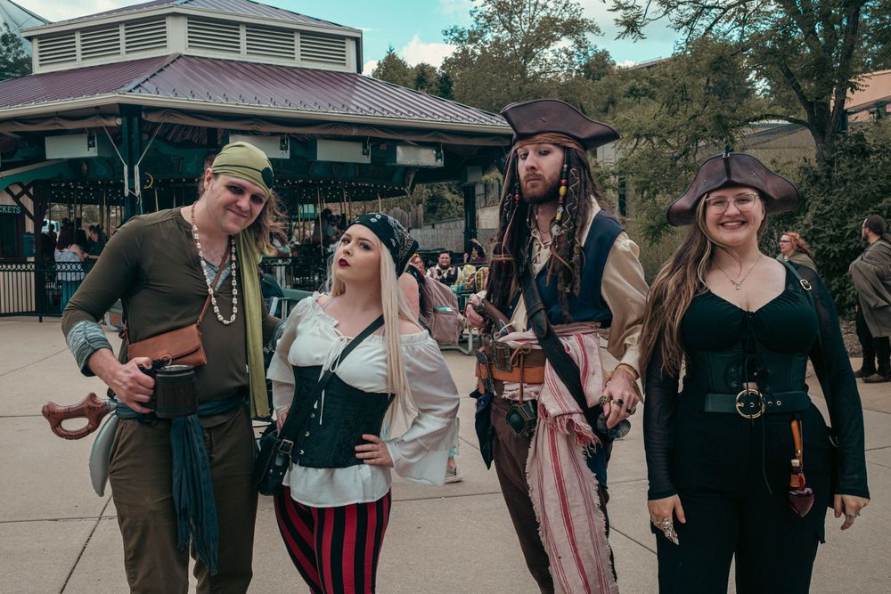 Group in medieval costumes posing together at a renaissance festival with period-appropriate clothing and accessories.