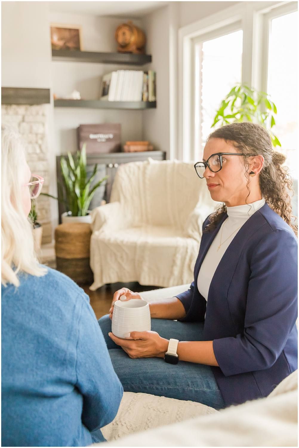 Woman talking with female client in living area while drinking coffee