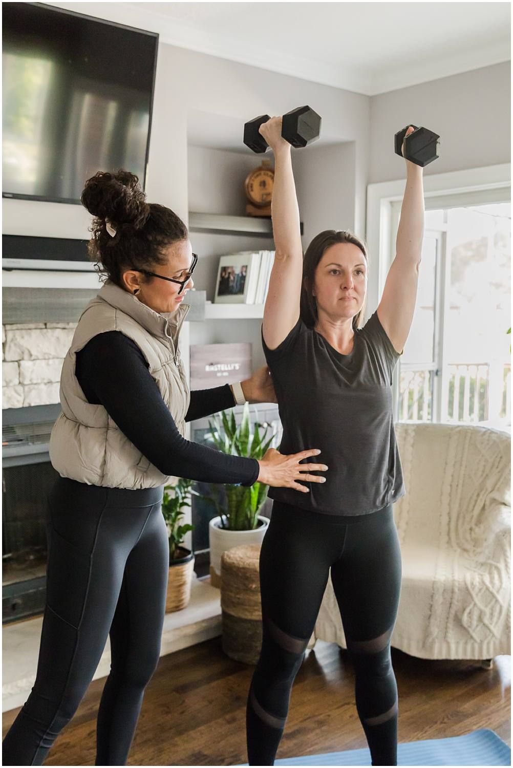 Woman helping female client with weight workout