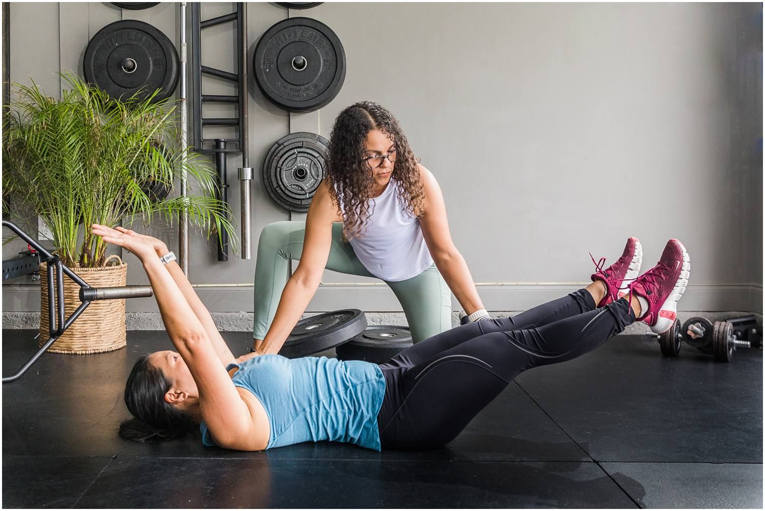 Fitness instructor helping female client with leg lifts