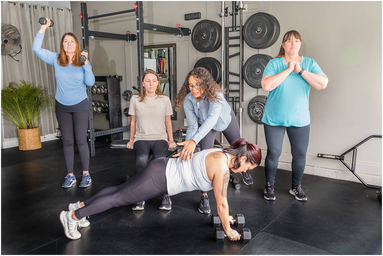 Fitness instructor helping female clients with weights and exercises