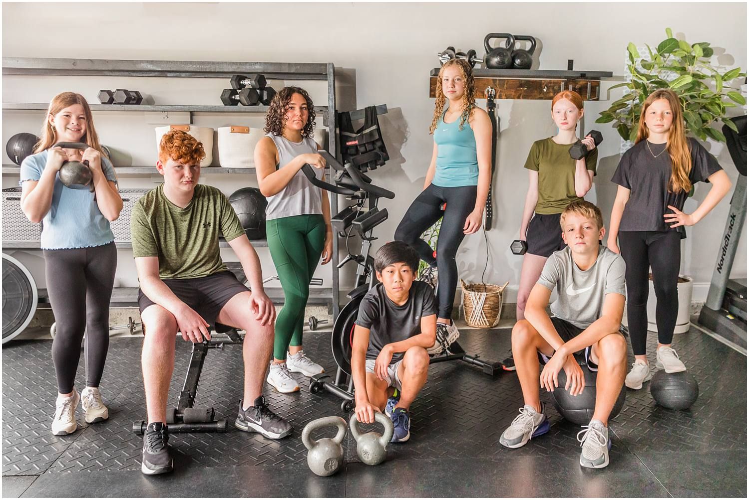 Male and female teenagers posing with gym equipment
