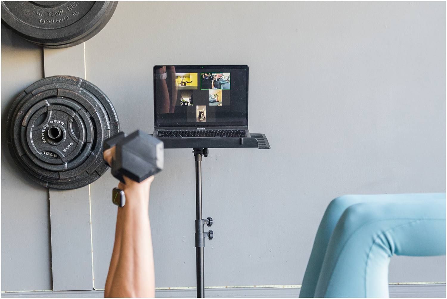 Arms holding weights with zoom clients on computer in background