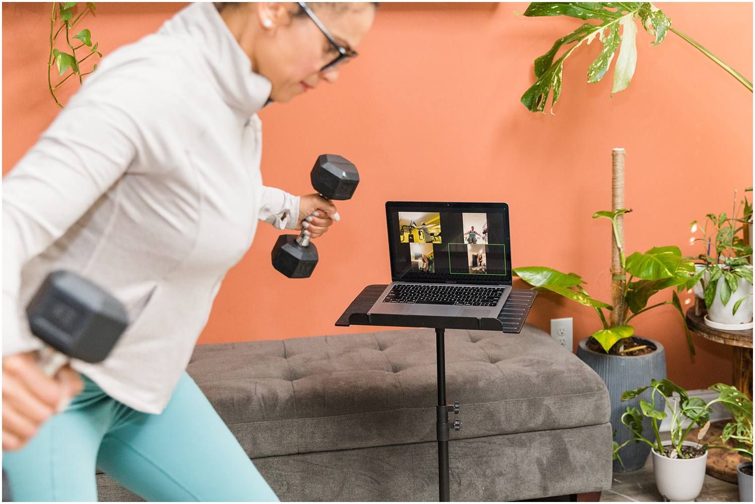Fitness instructor demonstrating arm weights on zoom call in living room