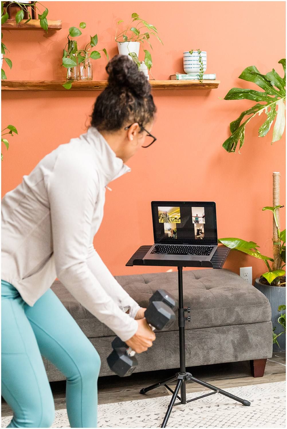 Fitness instructor demonstrating arm weights on zoom call in living room