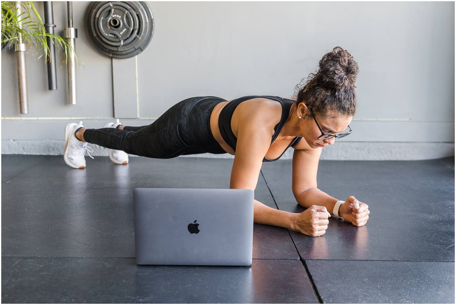Fitness instructor performing plank with computer in foreground